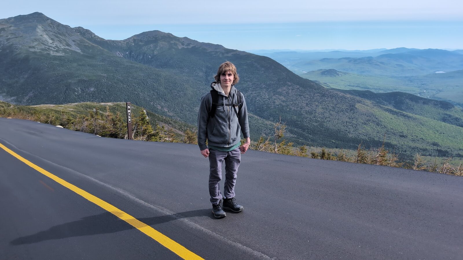 Hiker on the Mount Washington Auto Road on a clear summer day, Presidential Range and White Mountains valley stretching into the distance
