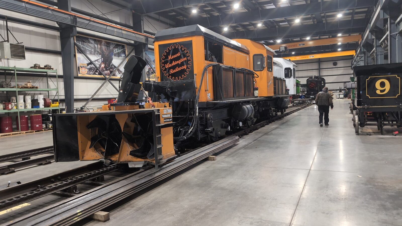 Mount Washington Railway orange diesel locomotive with snowblower attachment in the maintenance facility, historic car No. 9 visible at right